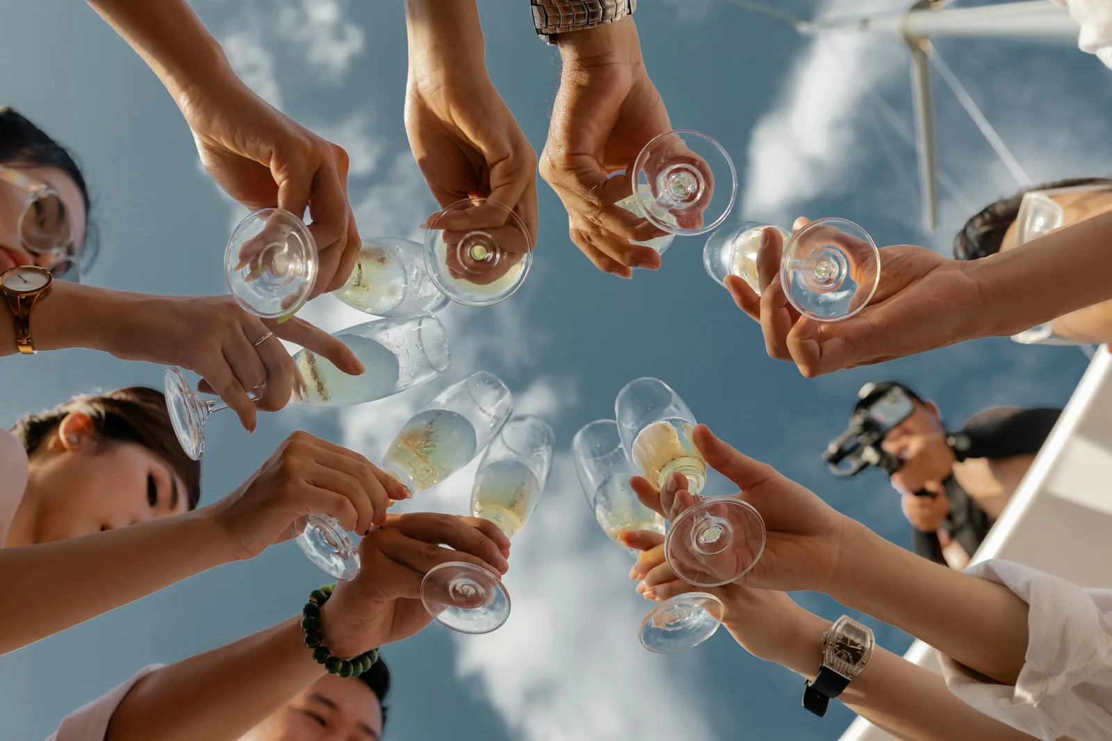 Friends celebrating outdoors with glass bottles raised.